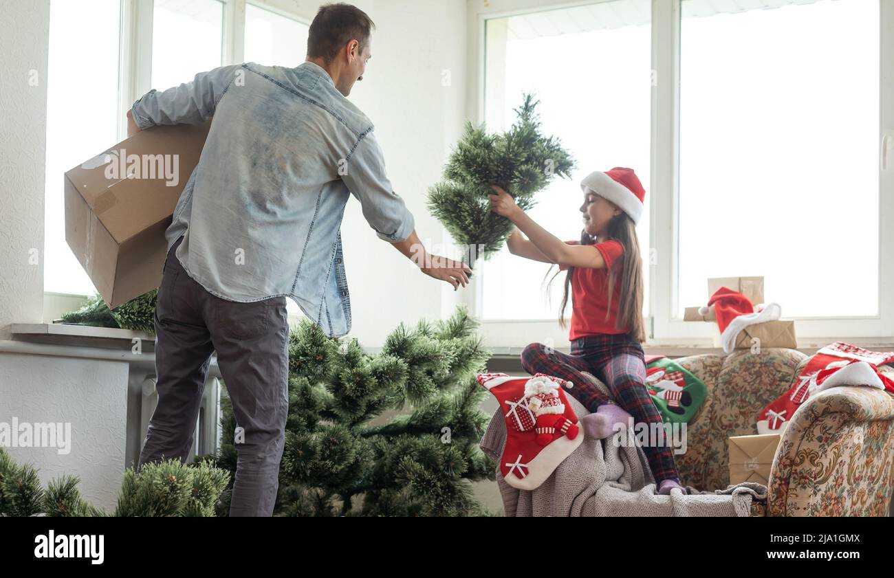 Father and little daughter decorating Christmas tree in room Stock ...