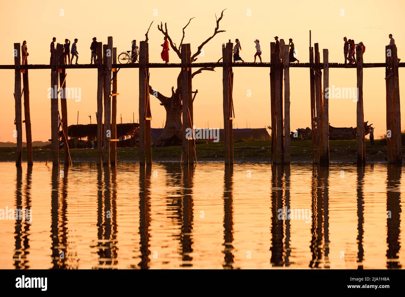 People walking on the U-Bein teak bridge in Amarapura at sunset, Mandalay, Myanmar. Stock Photo