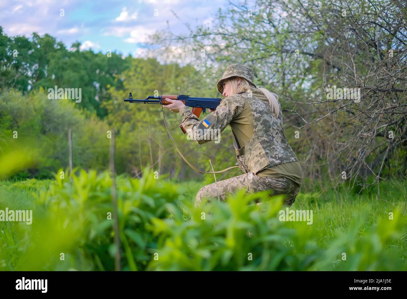 Ukrainian female soldier armed with an assault rifle patrols a combat ...