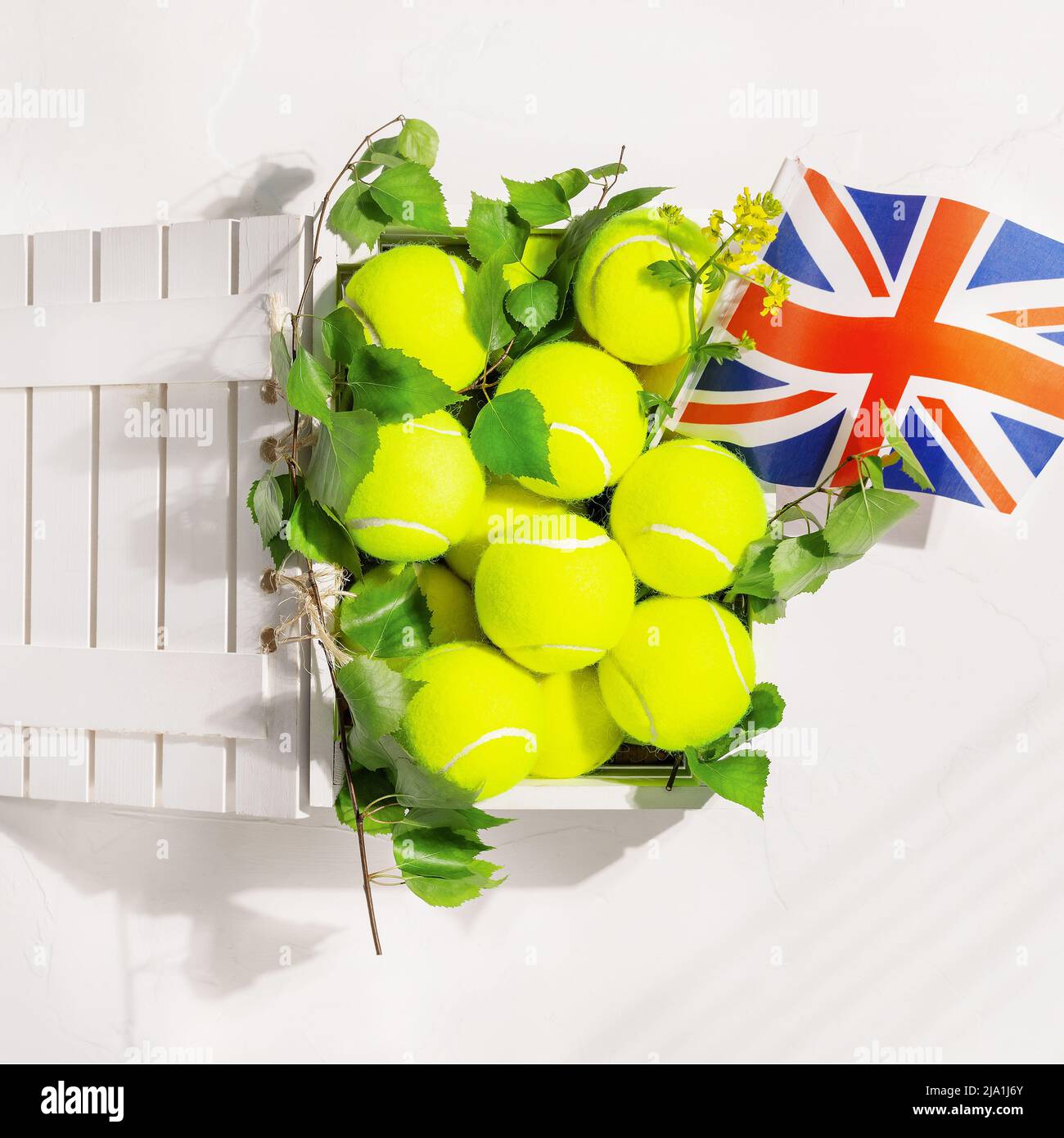 Yellow tennis balls in a wooden box and the flag of Great Britain Stock
