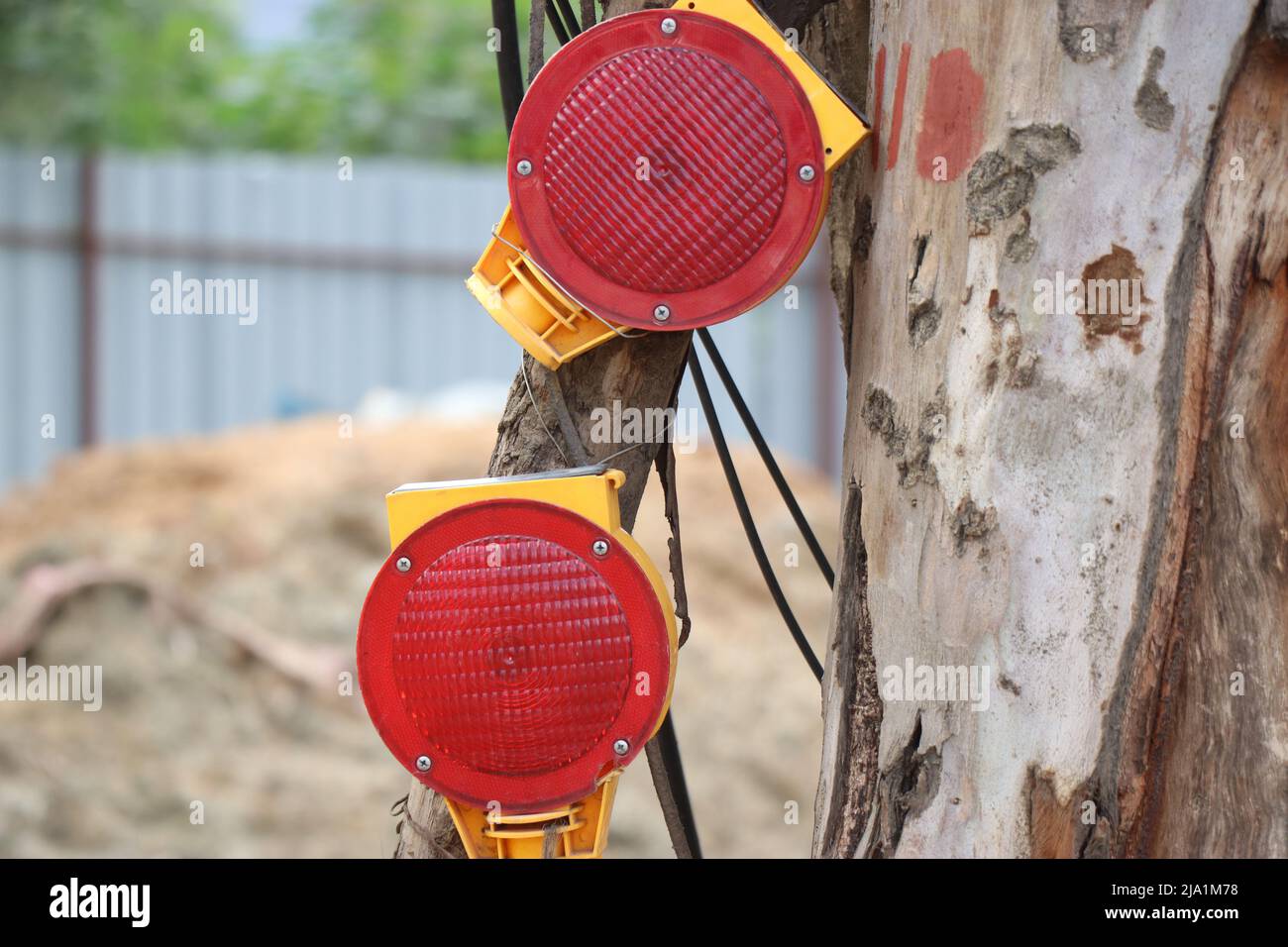 Red reflectors are attached to a wooden log by the side of a construction site which is a Security element Stock Photo