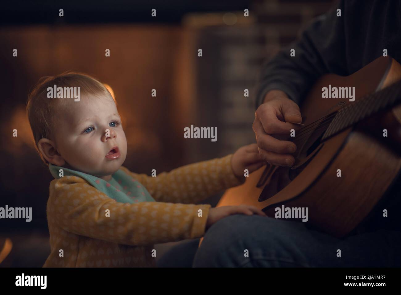 Baby watching a guitar being played Stock Photo