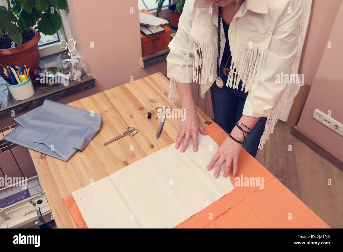 Overhead view of a fashion designer putting sewing pattern on a luxury ...