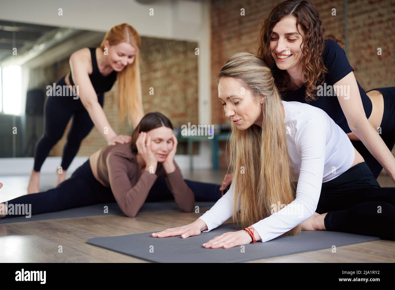 Group of young woman stretch legs in yoga studio. Stretching exercises ...