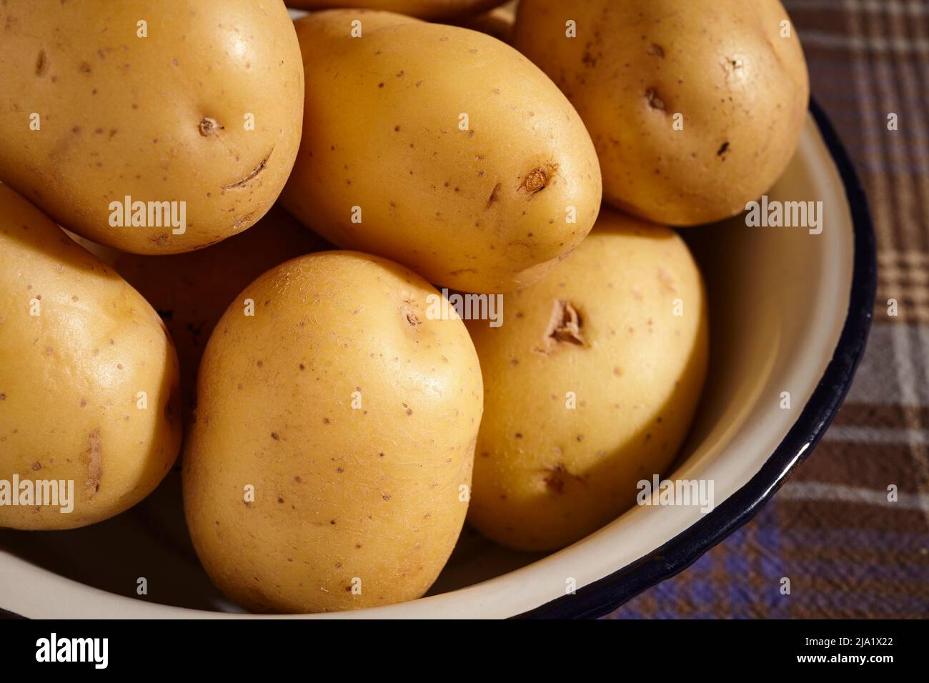Raw, whole, yukon gold, potatoes in a bowl Stock Photo