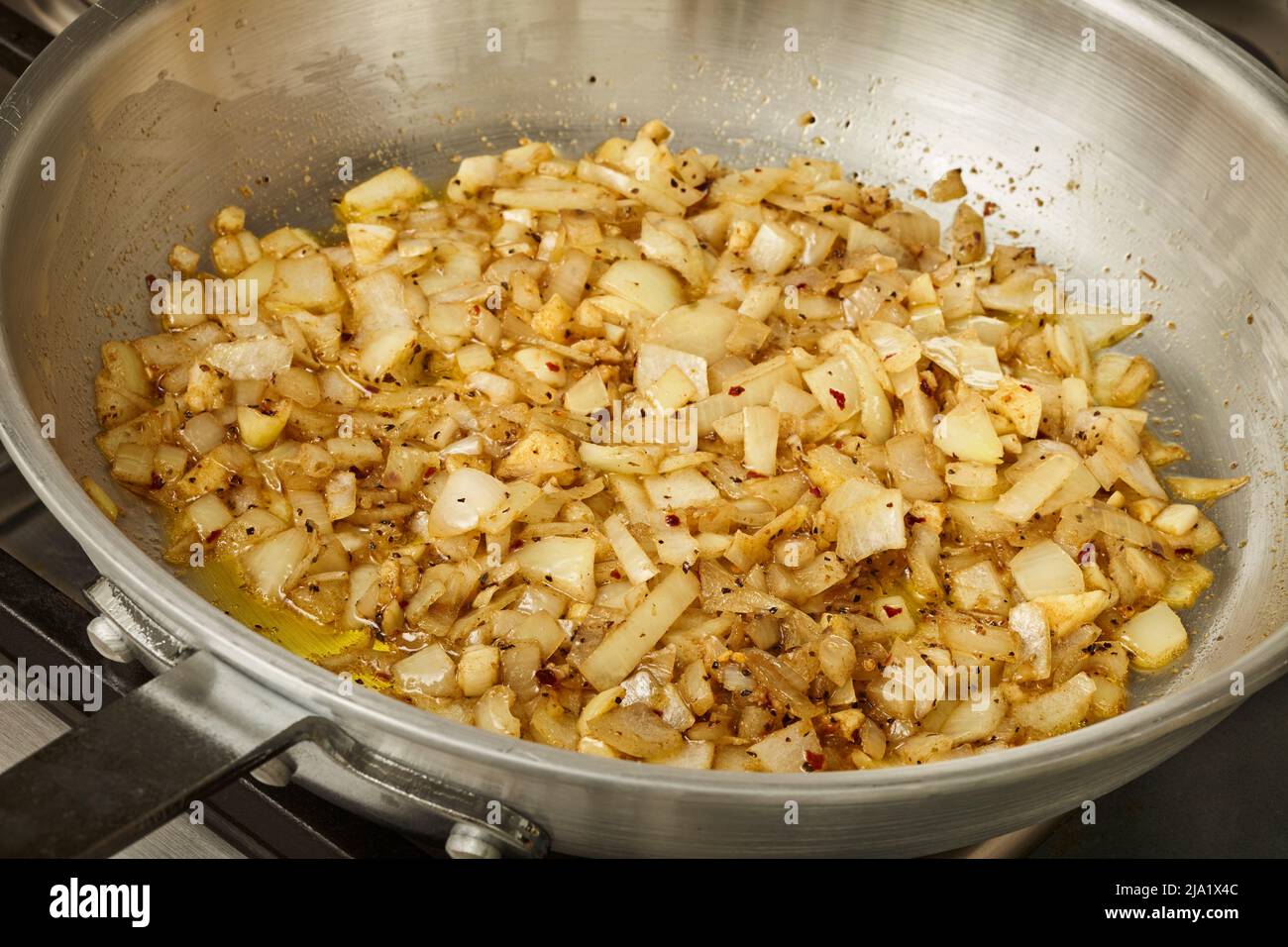 Onions caramelizing in a steel skillet Stock Photo