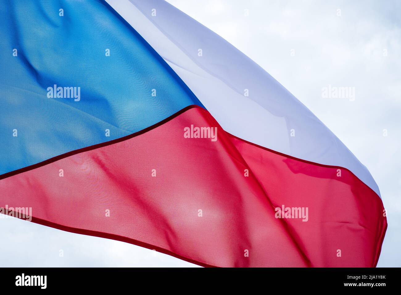 Czech flag waving in wind. Flag of Czech Republic on white cloudy sky background. Stock Photo