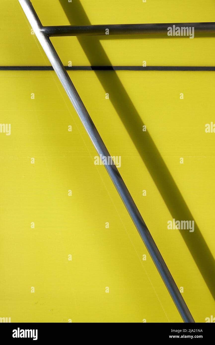 detail background image of metal bars against yellow green wall on a  sunny day Stock Photo