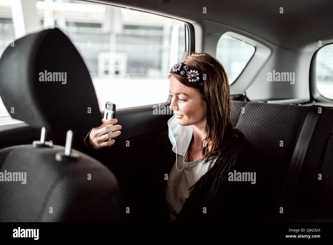 A taxi or Uber passenger talking through the phone on the car back seat Stock Photo