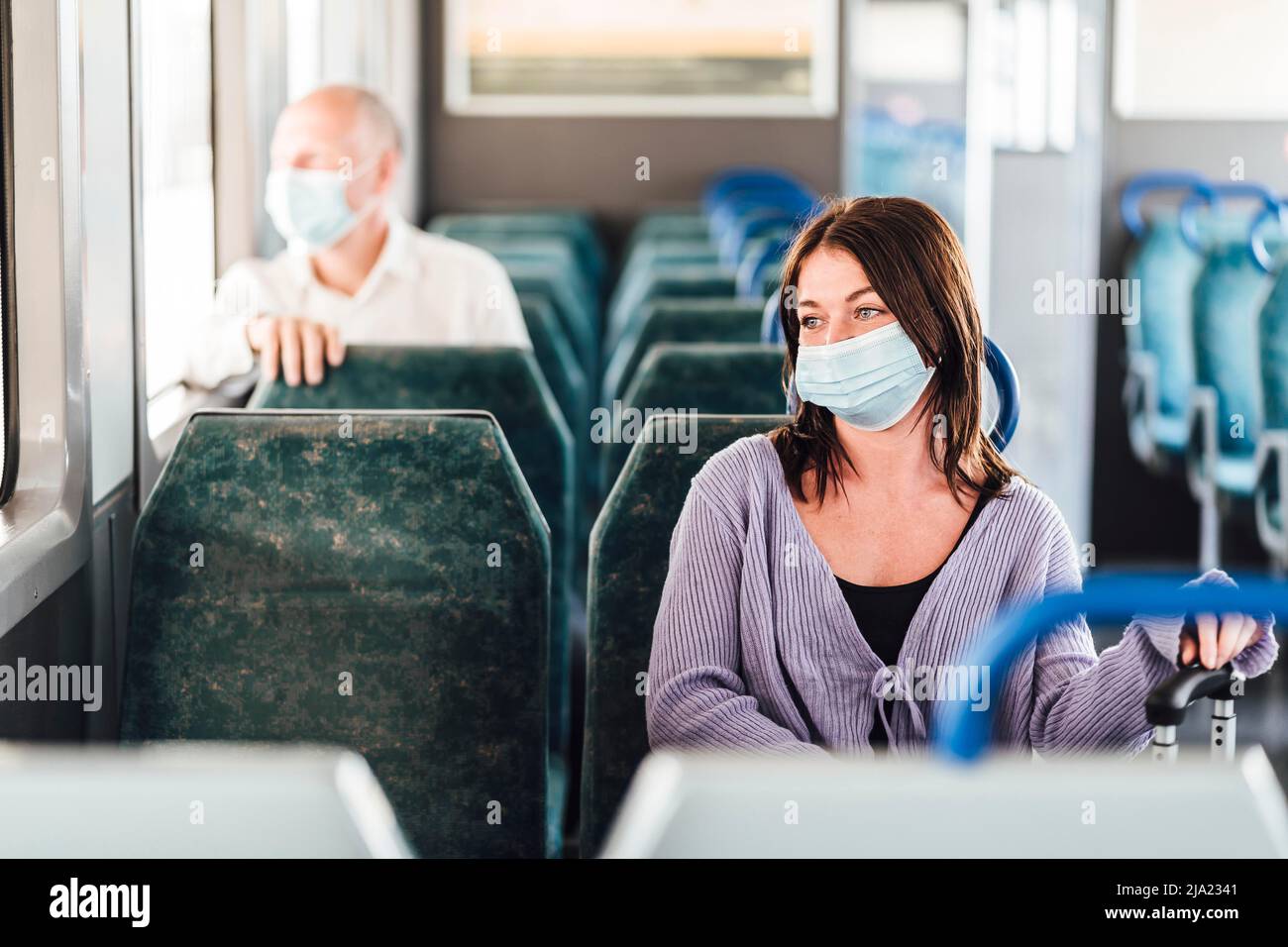 Serious passengers in protective masks during their train day trip Stock Photo