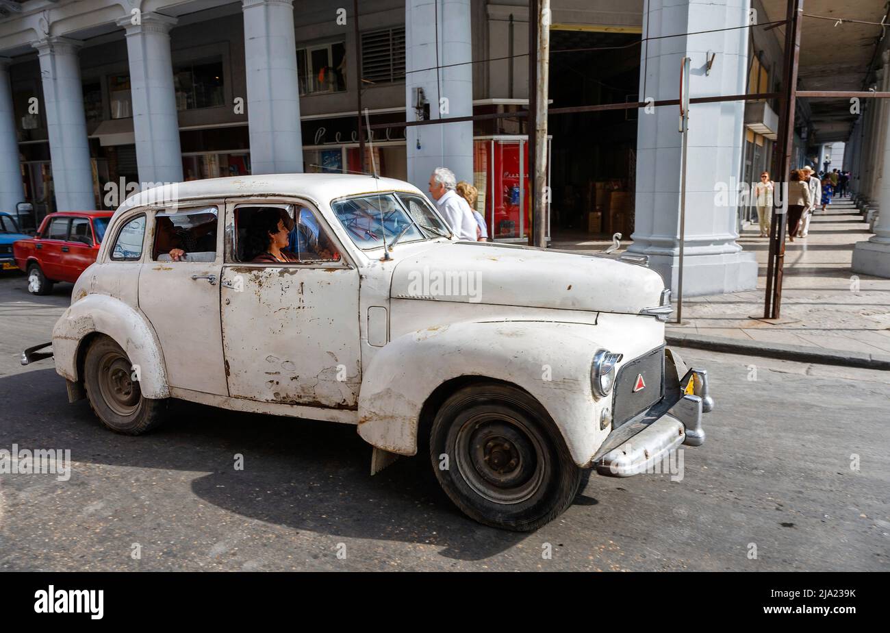 A battered, dilapidated, rusting vintage white American car is driven in the streets of downtown Havana, Capital city of Cuba - typical street scene Stock Photo