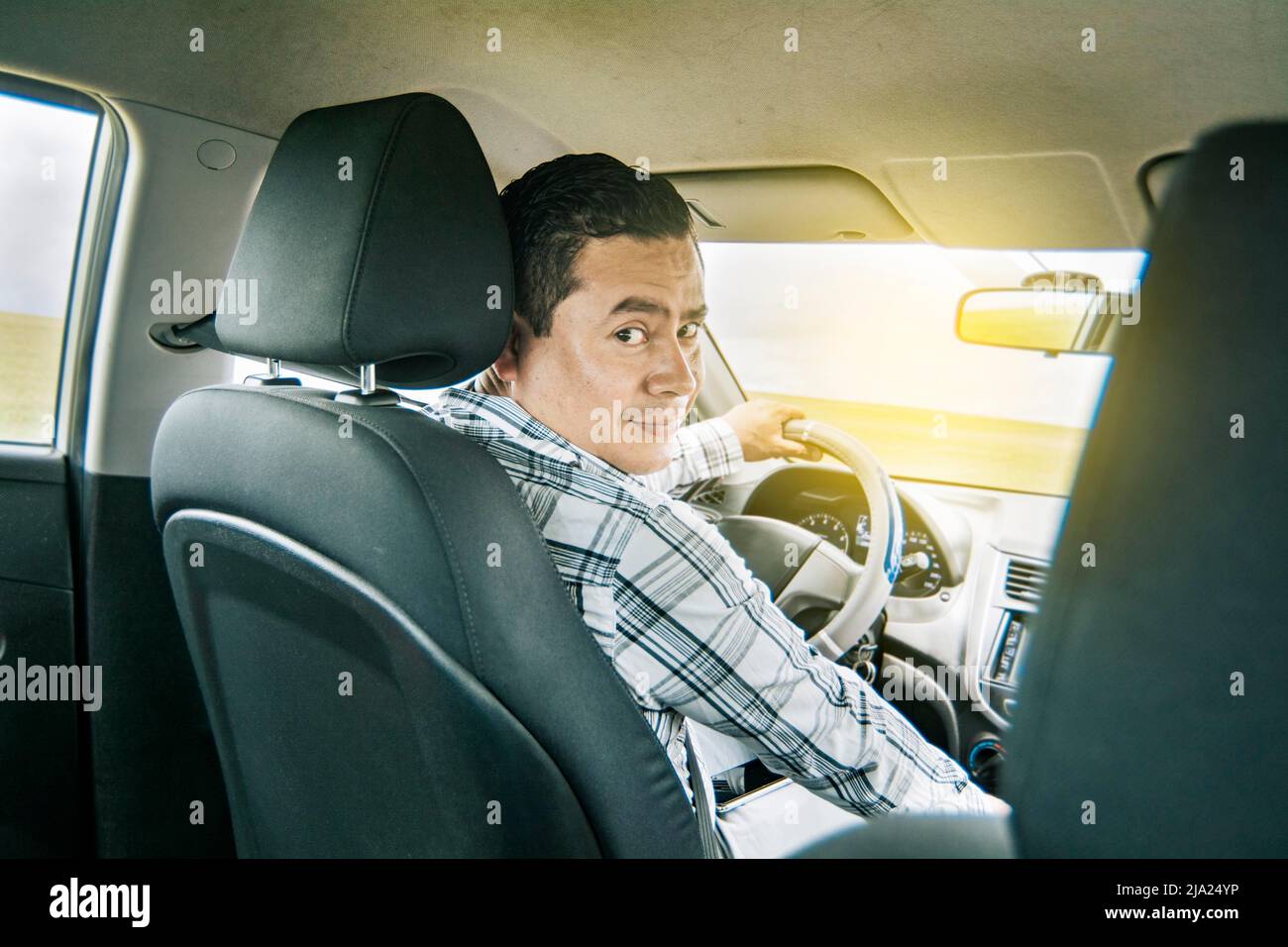 Happy young driver behind the wheel of a car. rear view of a smiling