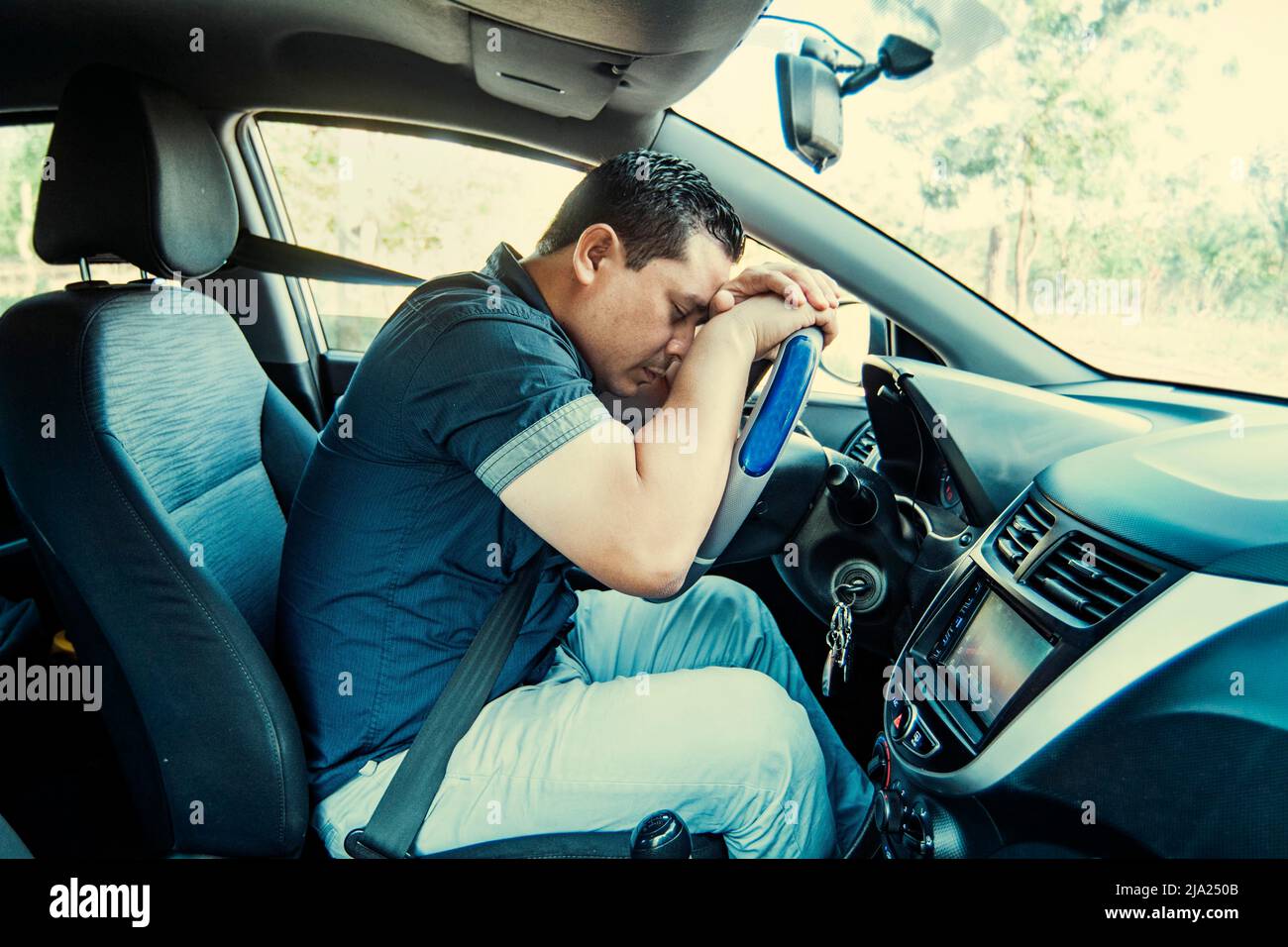 A tired driver asleep at the wheel, concept of man tired of driving. A man driver asleep at the wheel, A tired person sleeping at the wheel of the car Stock Photo