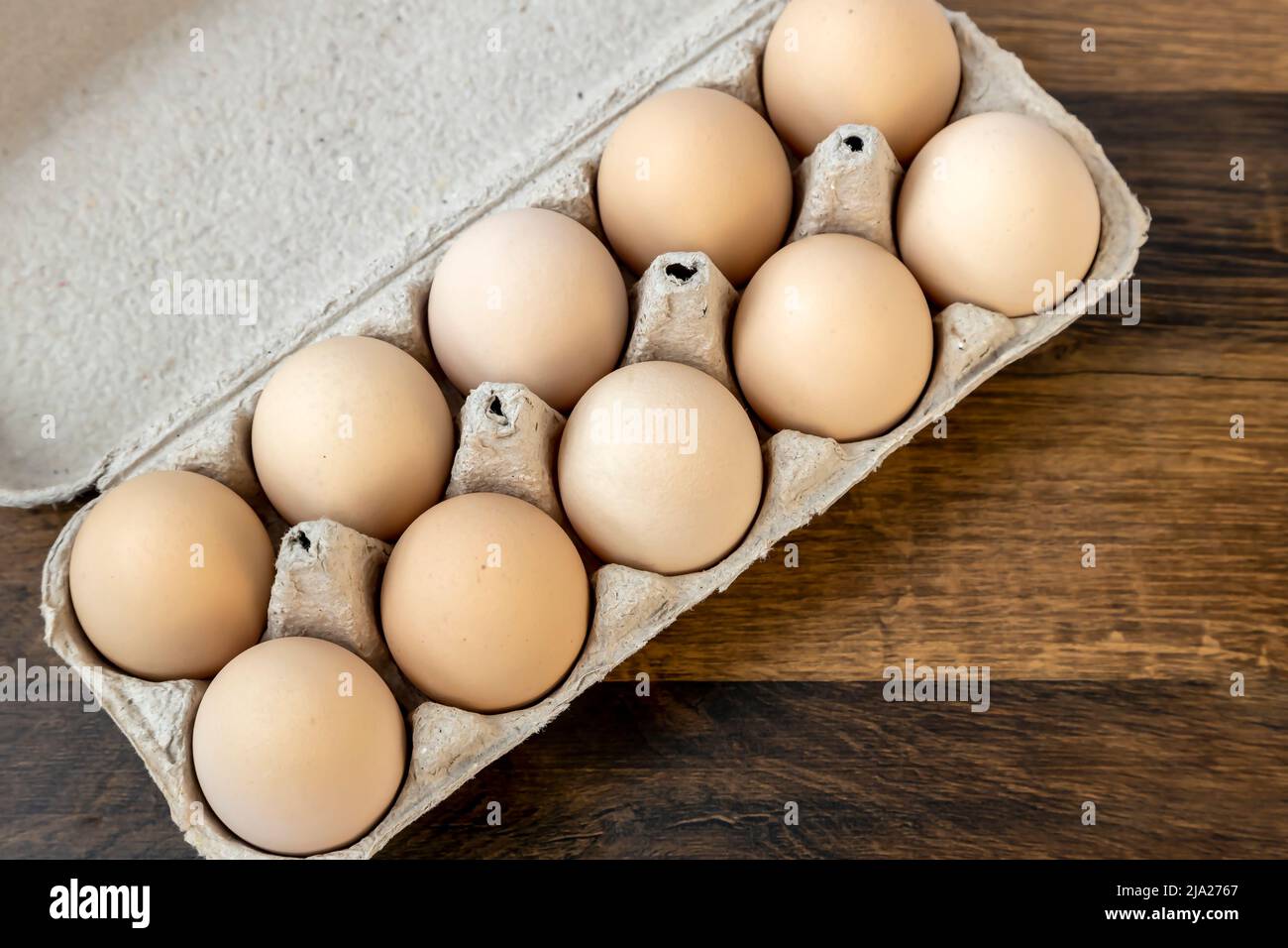 Top view, ten chicken eggs in a cardboard tray on the table. Stock Photo
