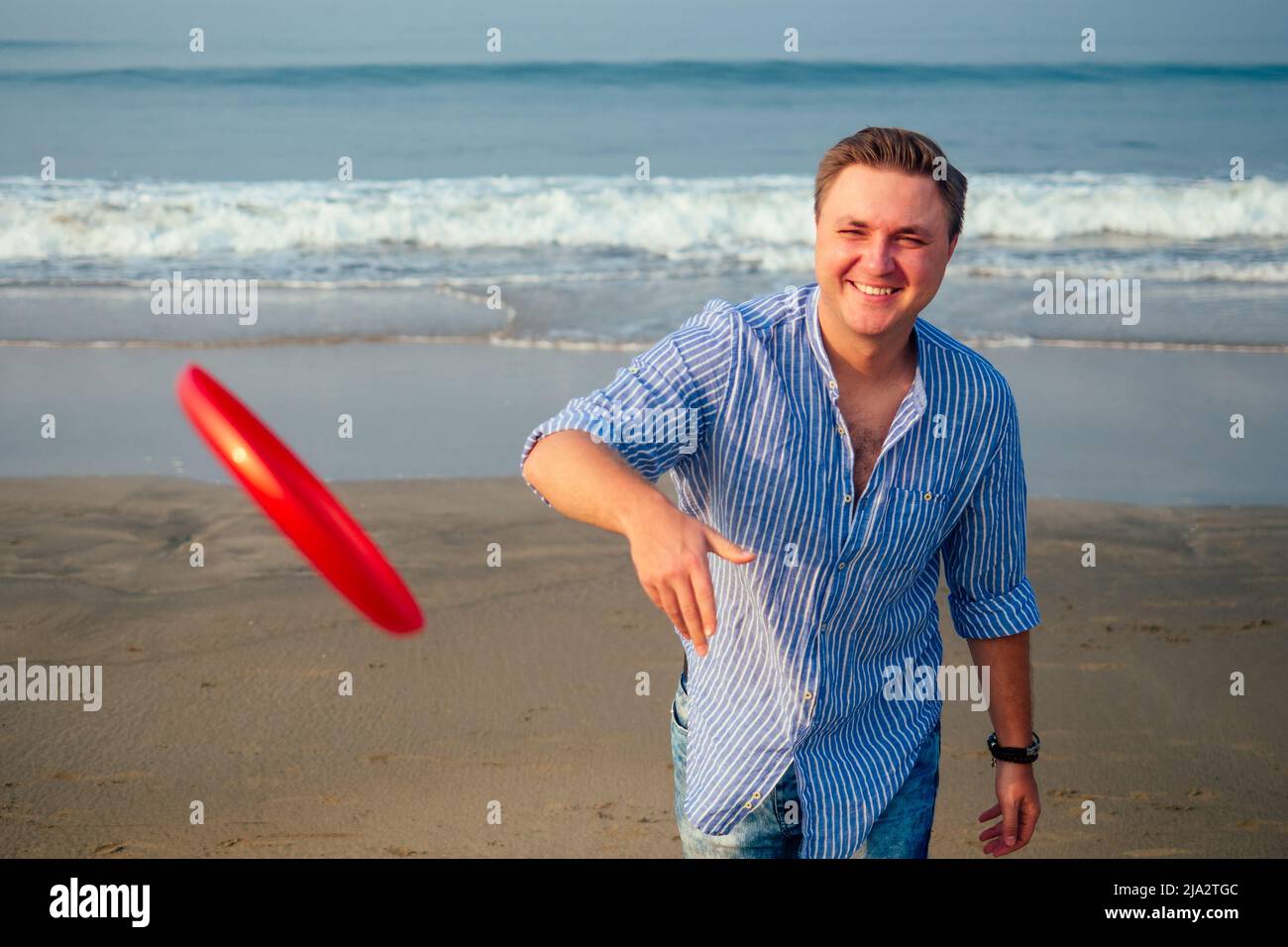 young man playing flying disk on the beach in the morning Stock Photo