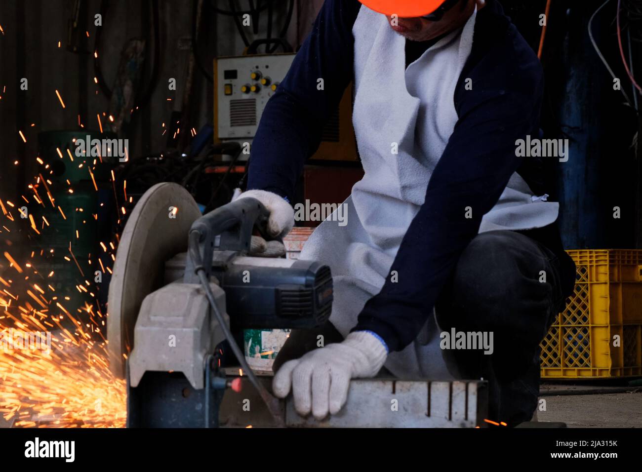 Professional men wearing goggles and construction gloves work in home workshop with electric steel cutter machine. Cutting metal makes sparks flying, Stock Photo