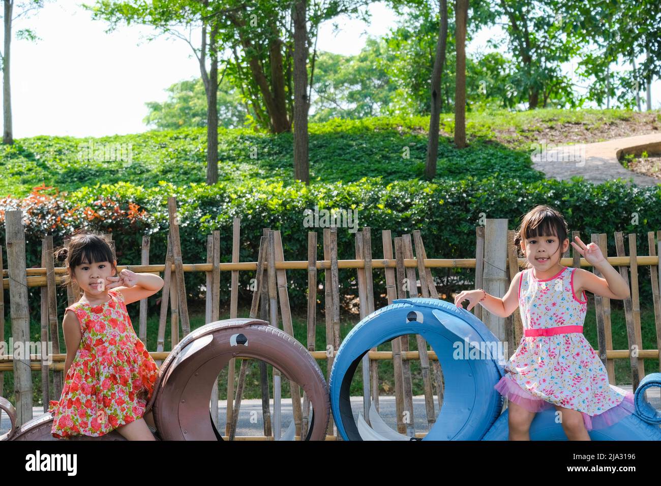 Cute little girl having fun in the outdoor playground. Young Asian sisters play together at school or kindergarten. Healthy summer activity for childr Stock Photo