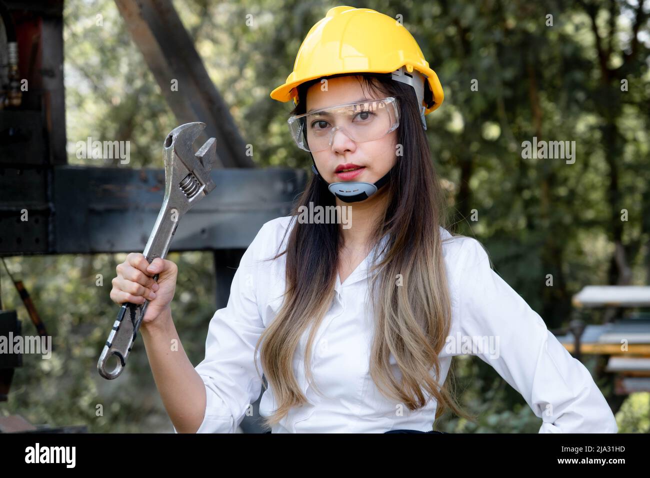 Asian female engineering worker with industrial wrench in workshop. Engineer woman working in manufacturing business. Profession and Construction Work Stock Photo