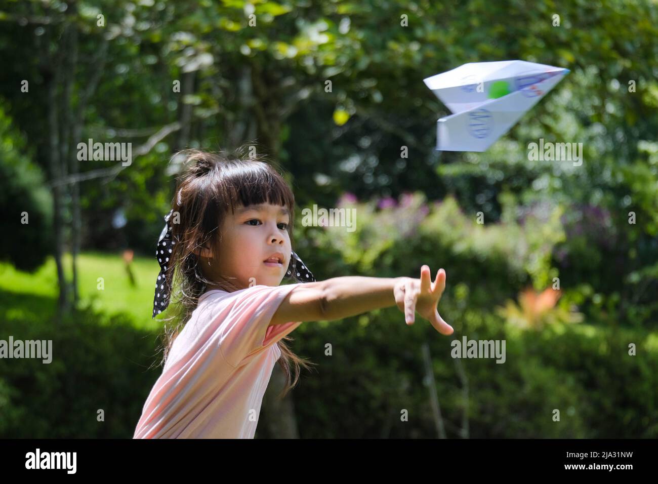 Happy children playing with paper airplane in the summer garden. Cute ...