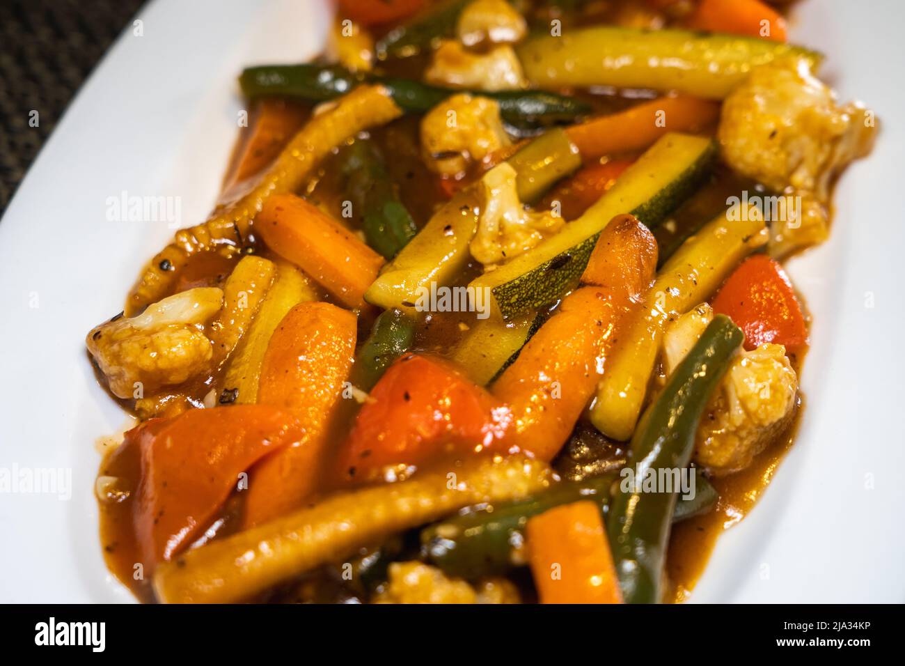Sautéd exotic vegetables - Zucchini, Baby corn, Broccoli, Beans, Carrots, Mushrooms, Cauliflower and Bell Peppers mixed in black pepper sauce. Stock Photo