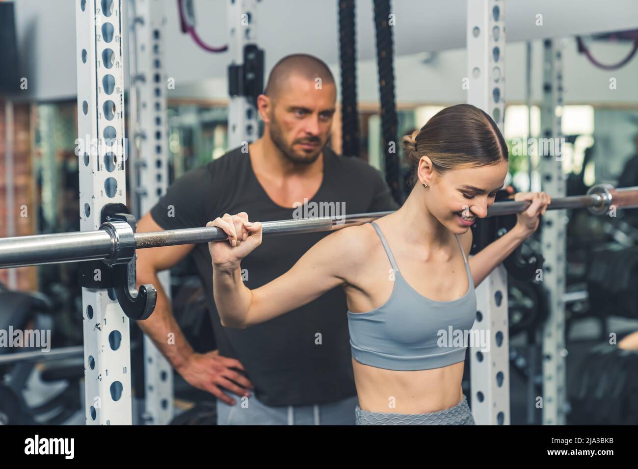 Portrait of a caucasian sportswoman under the supervision of a coach doing physical exercise with a dumbell in gym in daytime. High quality photo Stock Photo