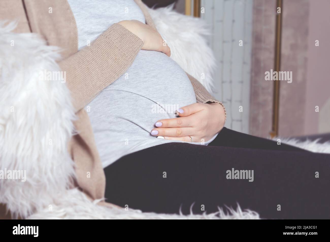 Pregnant woman holding belly. Sitting in chair Stock Photo Alamy
