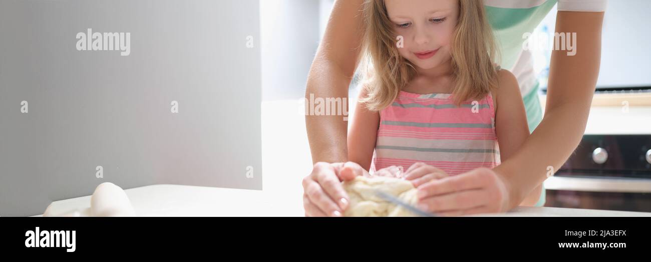 Mom and daughter are kneading dough together in the kitchen Stock Photo ...