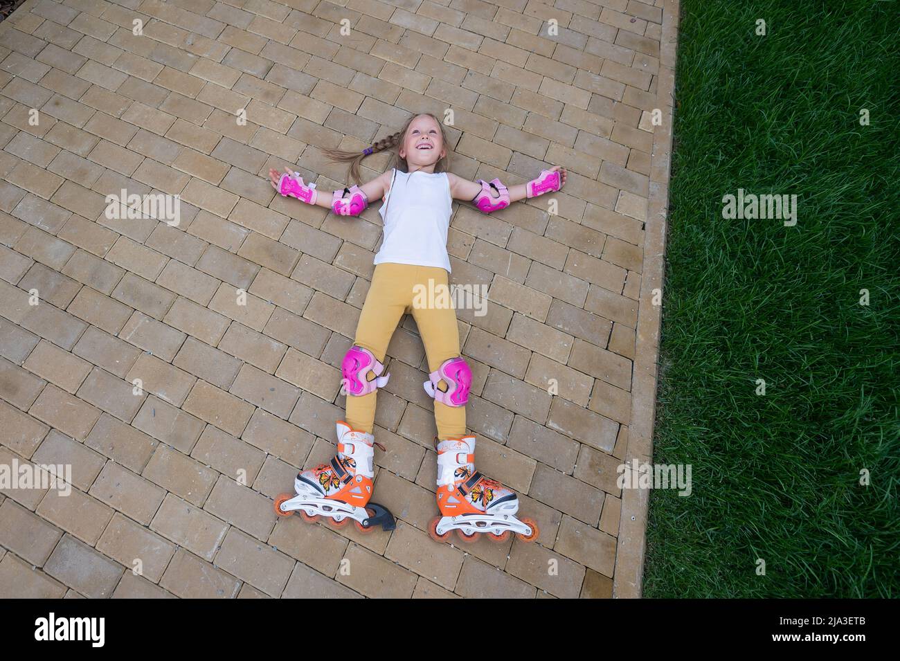 Little girl learns to roller skate and falls. View from above Stock