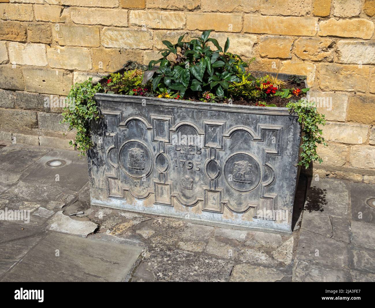 Old lead box, now re-used as a planter, outside the Lygon Arms Hotel, in the Cotswold town of Broadway, Worcestershire, UK Stock Photo