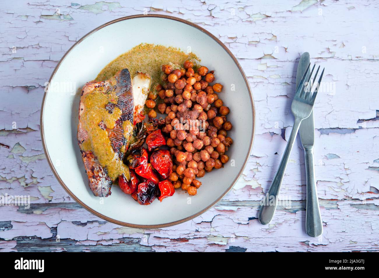 A freshly cooked fillet of Sea Bass served with roasted tomatoes and chick peas. A healthy,nutritious, meal option high in omega 3 fatty acids Stock Photo