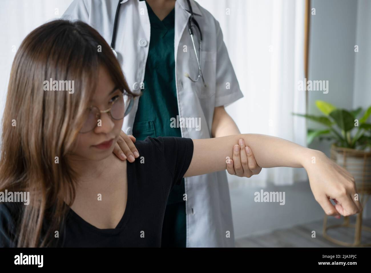 Female patient is exercising treatment with physiotherapist after arm