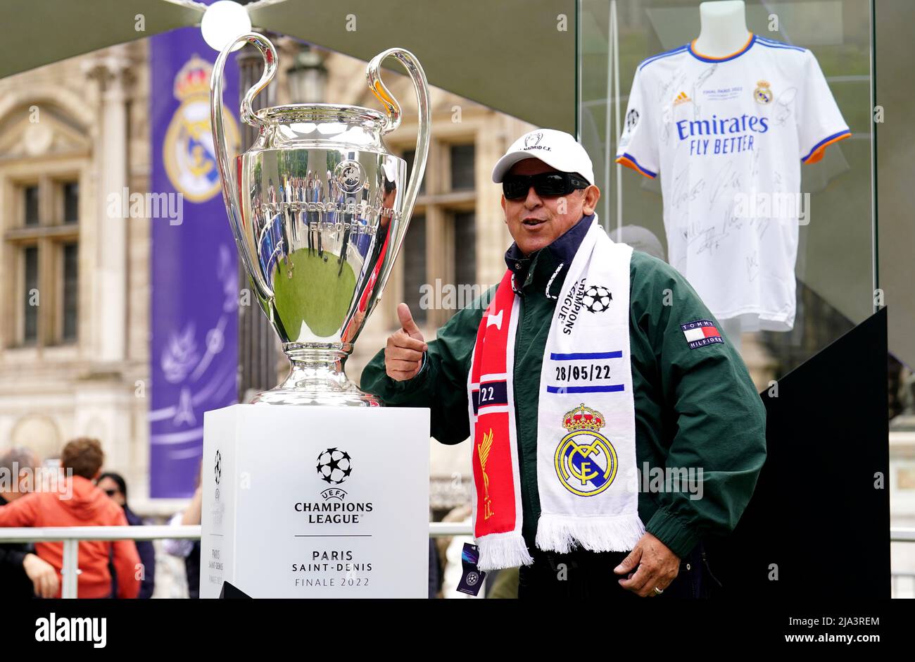A fan poses next to the UEFA Champions League trophy at the Trophy Experience at The Place de l'Hotel de Ville in Paris ahead of Saturday's UEFA Champions League Final at the Stade de France, Paris. Picture date: Friday May 27, 2022. Stock Photo