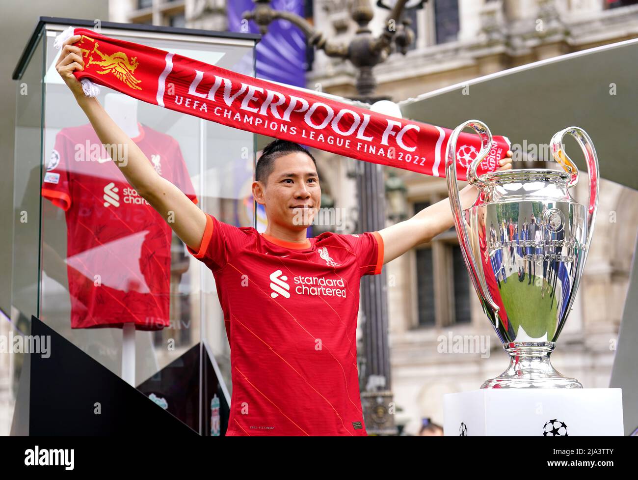 A Liverpool fan poses next to the UEFA Champions League trophy at the Trophy Experience at The Place de l'Hotel de Ville in Paris ahead of Saturday's UEFA Champions League Final at the Stade de France, Paris. Picture date: Friday May 27, 2022. Stock Photo