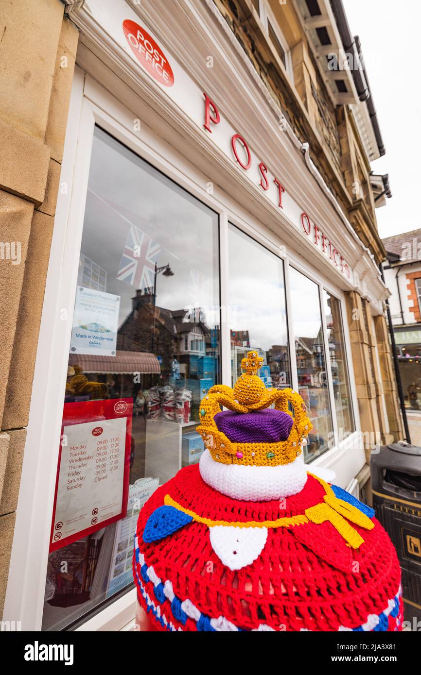 UK Platinum Jubilee of Elizabeth II 27May 2022 .Windermere Village Cumbria .Crochet Crown on pillar box at Post Office Windermere Village .Sub post master, Nigel Bartlett looks after the crown made by 'Handmade by Lakeland Old Maid' AKA Jane Glover, Credit: Gordon Shoosmith/Alamy Live News Stock Photo