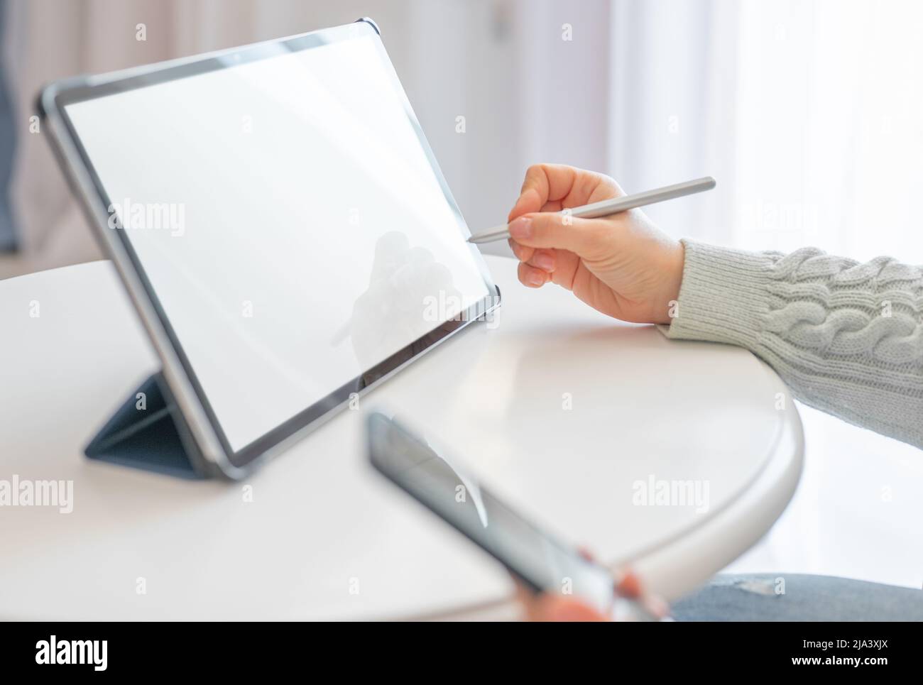 Close-up of woman working with stylus and digital tablet pc. Close up business woman hand using electronic or stylus pen, work on digital tablet at ho Stock Photo