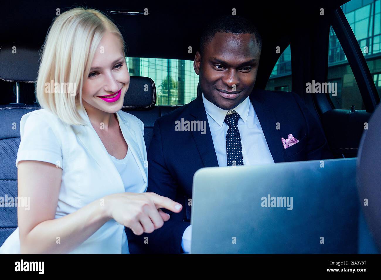 beautiful successful blonde short haircut business woman with makeup in white business dress with a handsome Afro-American man in black stylish suit Stock Photo