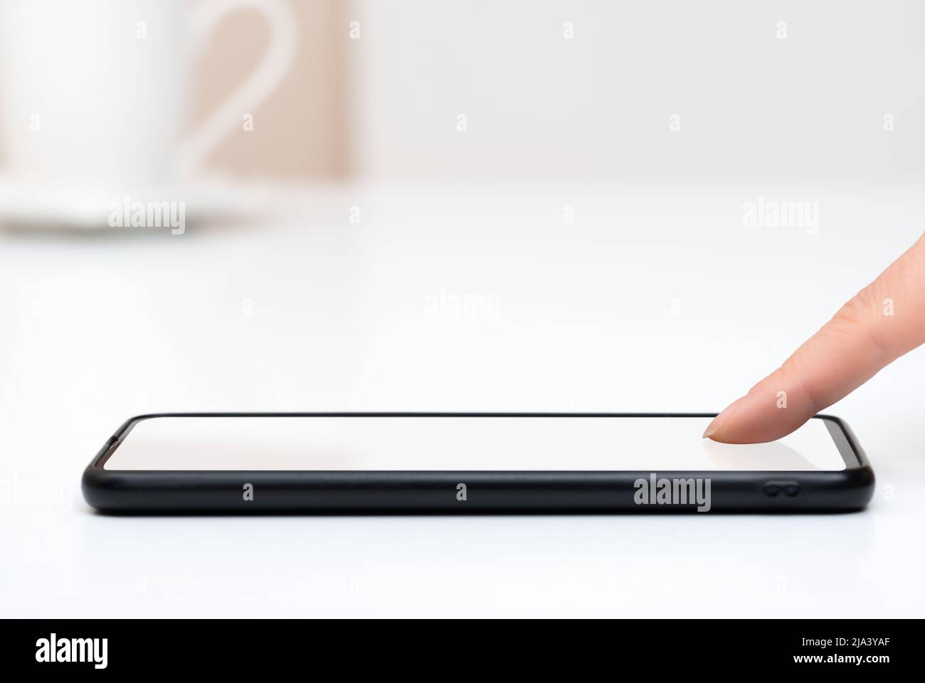 woman tapping on phone blank white screen. Smart phone on white table