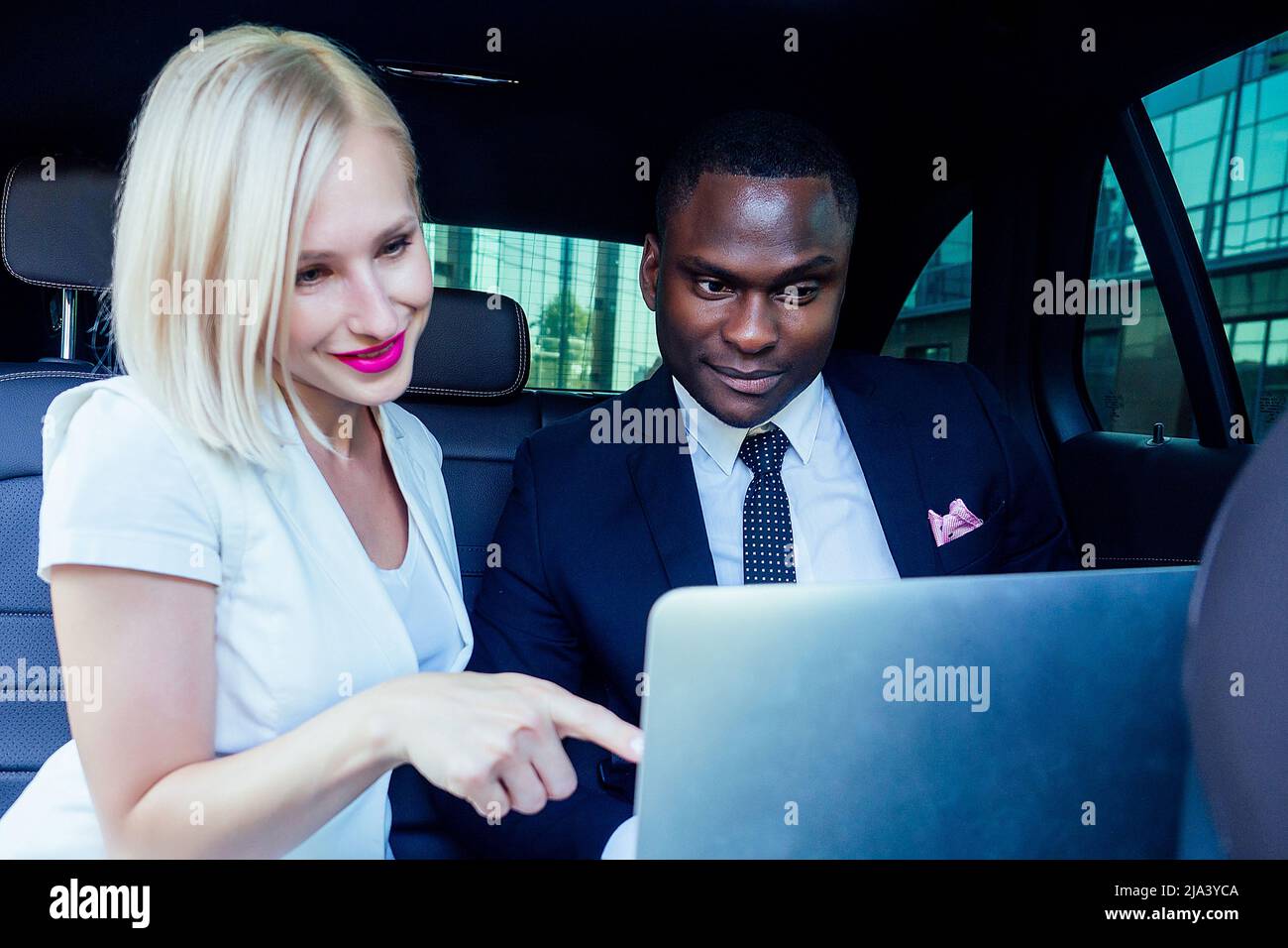 beautiful successful blonde short haircut business woman with makeup in white business dress with a handsome Afro-American man in black stylish suit Stock Photo