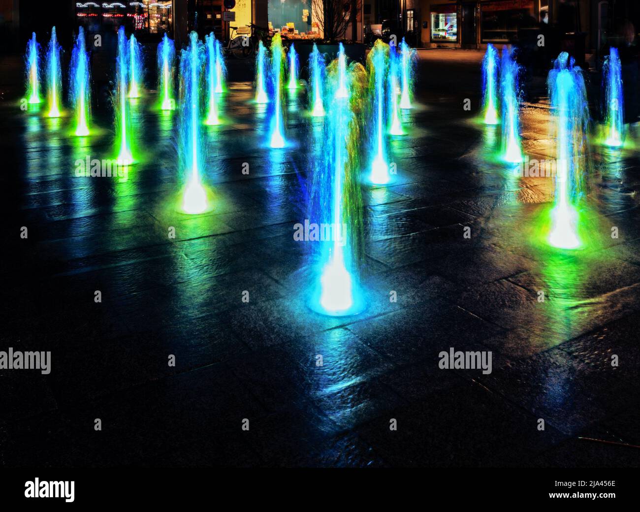 Colourful illuminated waterspout fountain at night Stock Photo