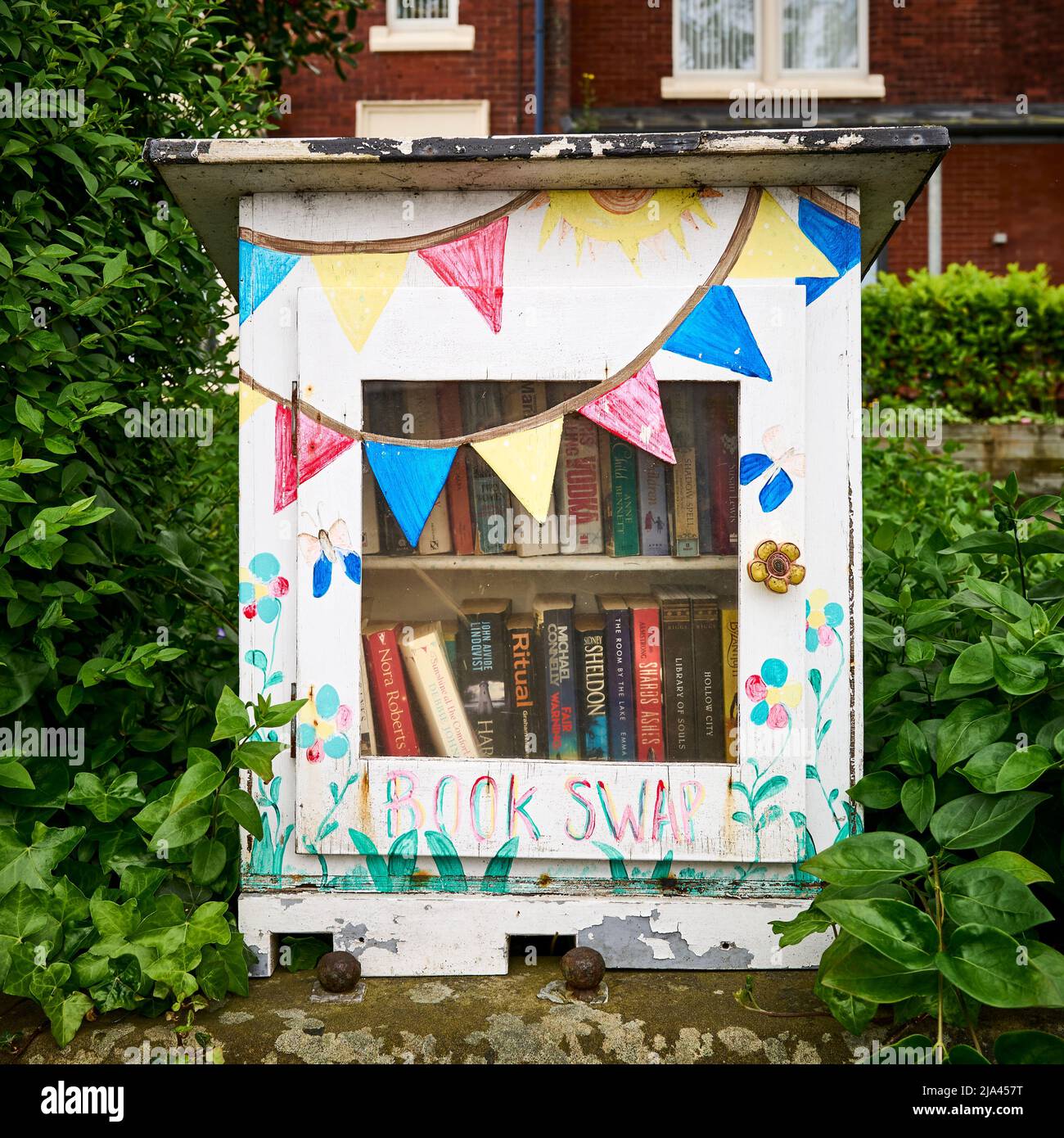 Book swap box on garden wall Stock Photo