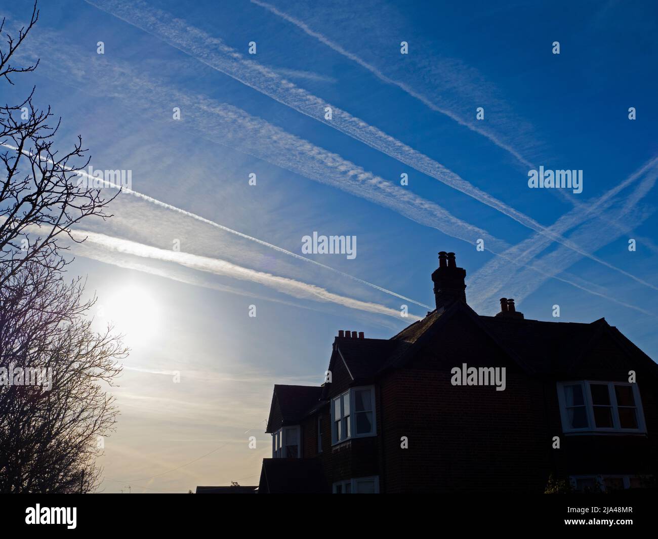 Luminescent dawn sky packed with contrails, seen above Sandford Village, just south of Oxford. Stock Photo