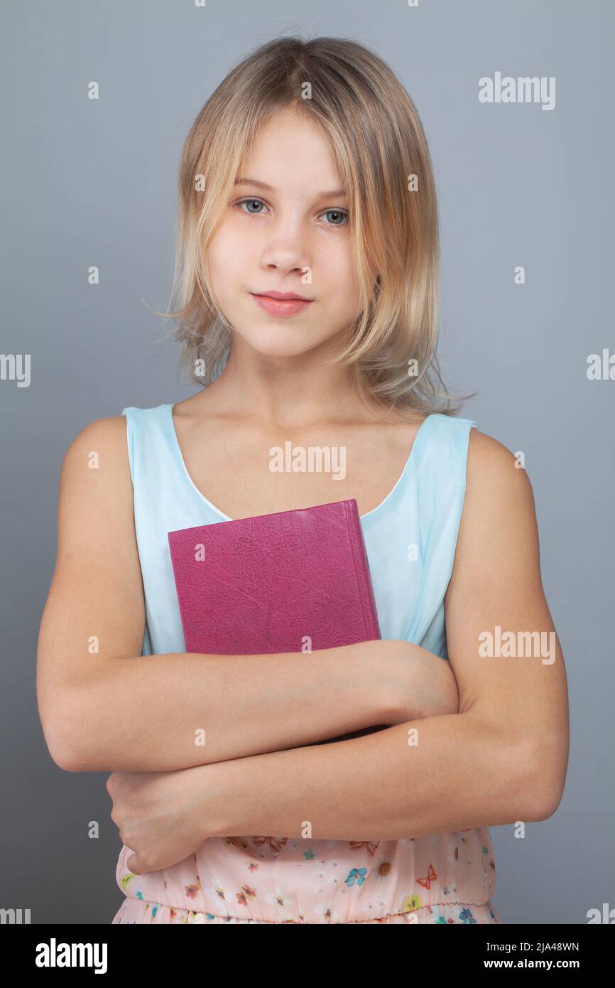 Little child girl holding book on gray background Stock Photo - Alamy