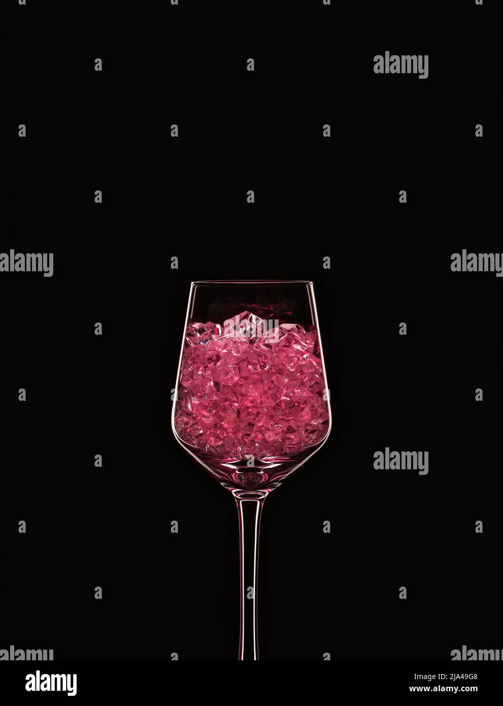 Wine glass filled with transparent pink crystals backlit and isolated on black background. Beverage glassware concept. Copy space. Stock Photo