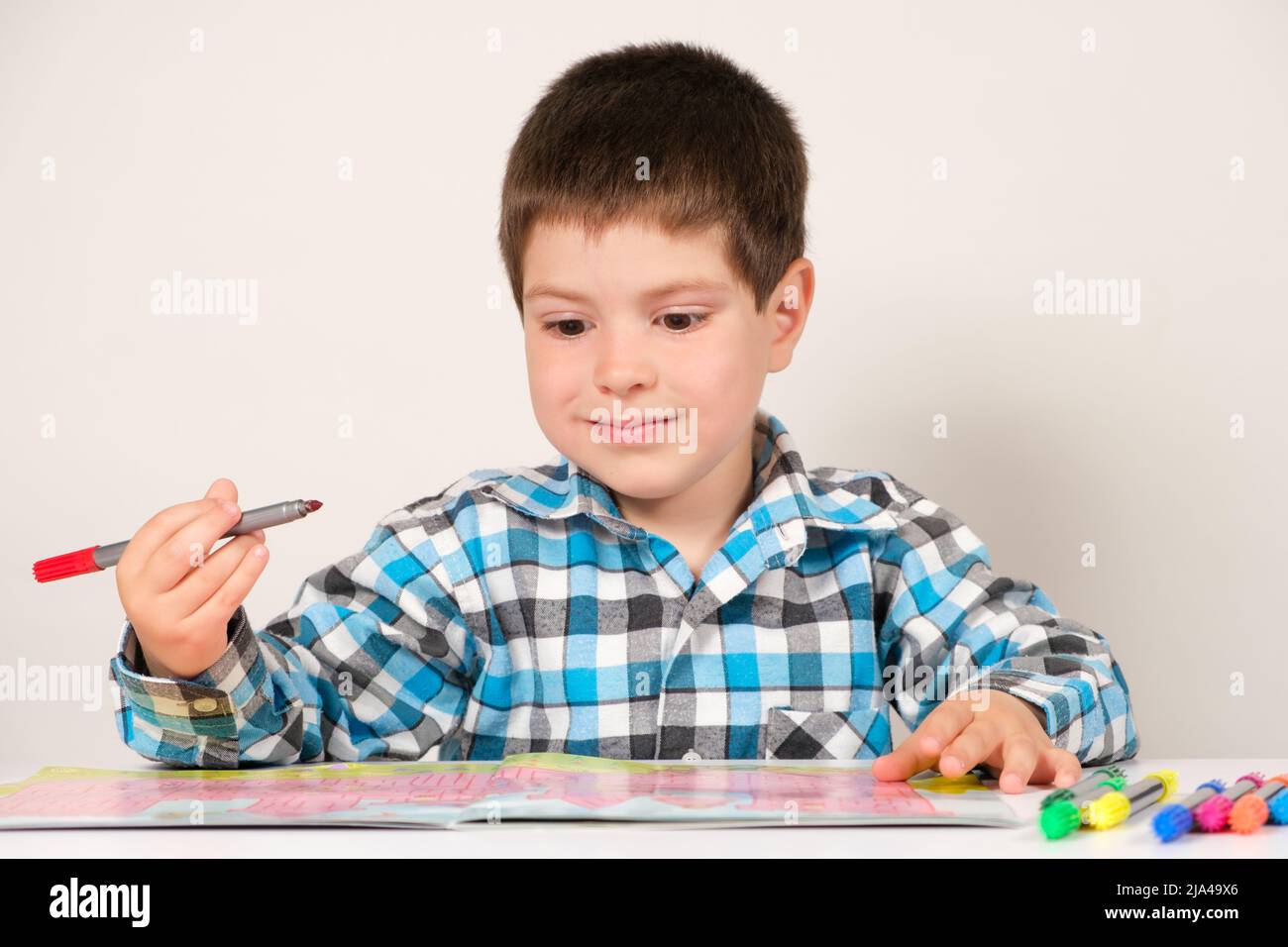 A preschool boy studies and passes labyrinths on a white background ...