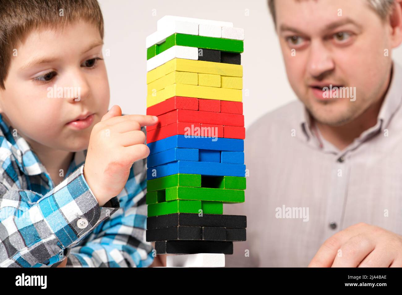 Dad and son play a board game together, pull parts out of the tower and try not to overwhelm the tower Stock Photo