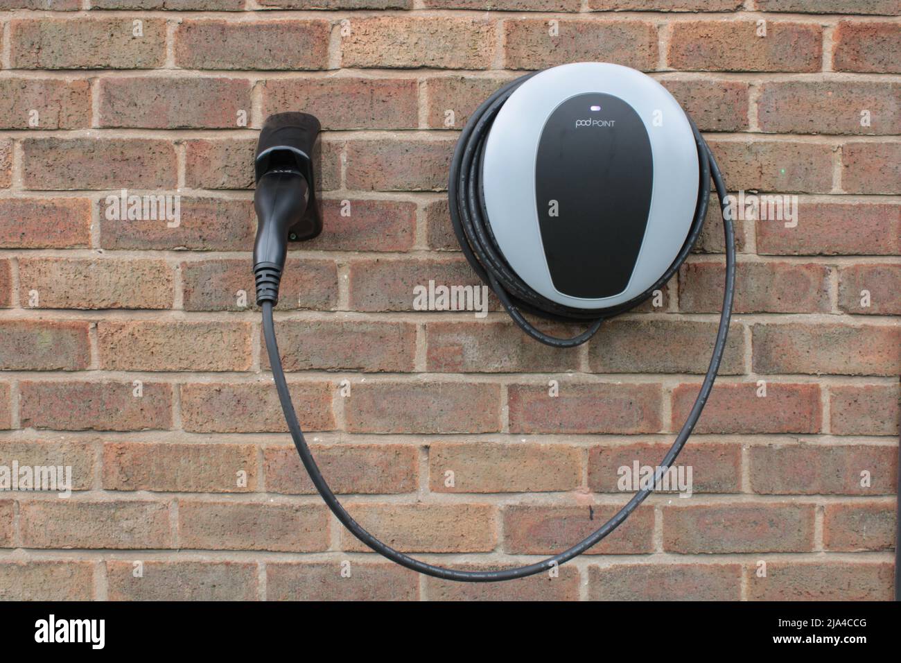 Home charging point. Pod Point domestic electric vehicle charging point mounted on a brick wall. Lancashire, UK Stock Photo