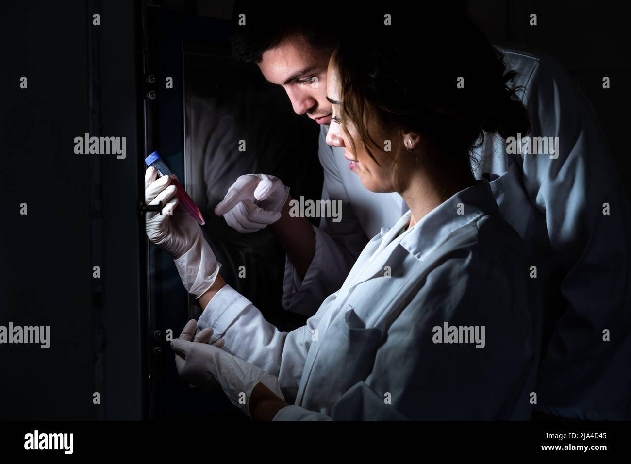 Two smiling scientist in lab coat holding and studying a medium tube