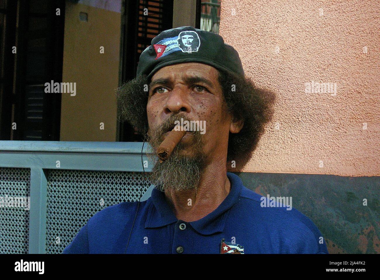Bearded old cuban man with Che Guevara cap smoking a big cigar, Cathedral Plaza, historic old town of Havana, Cuba, Caribbean Stock Photo