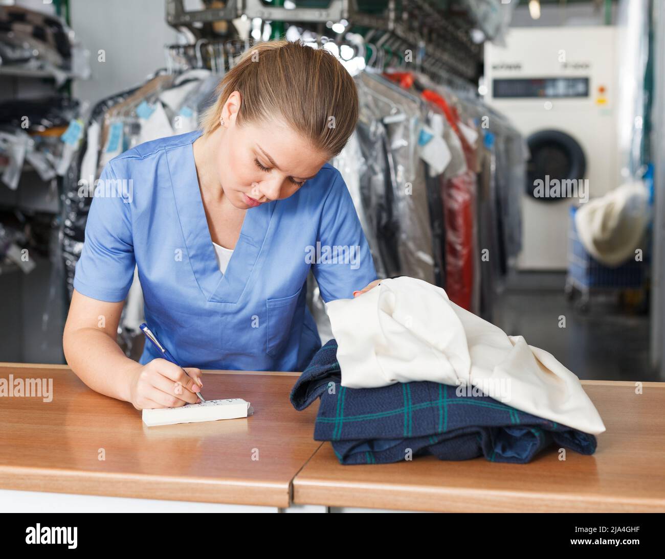 Worker of laundry writing receipt Stock Photo Alamy