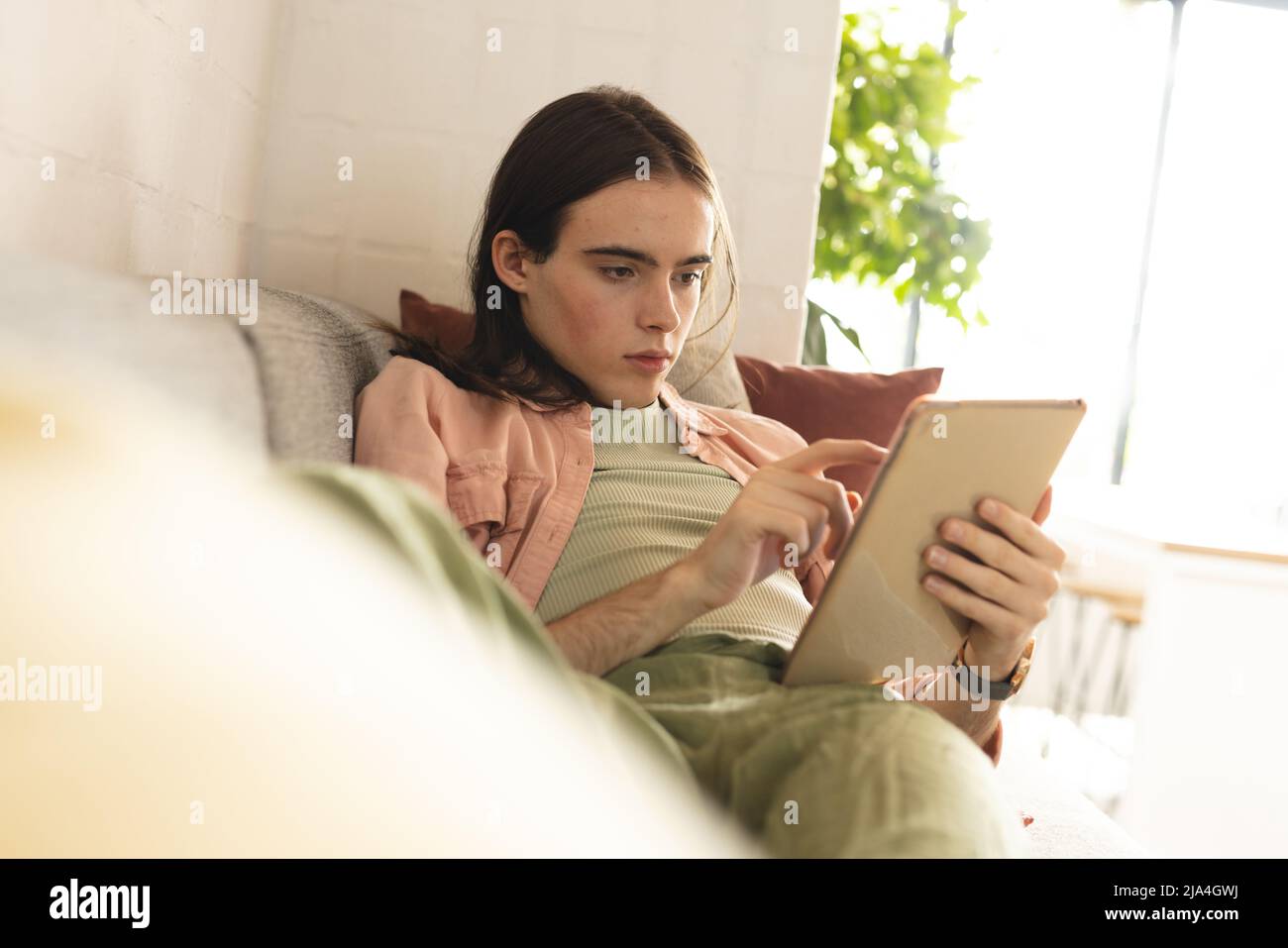 Nonbinary trans woman using digital tablet lying on the couch at home